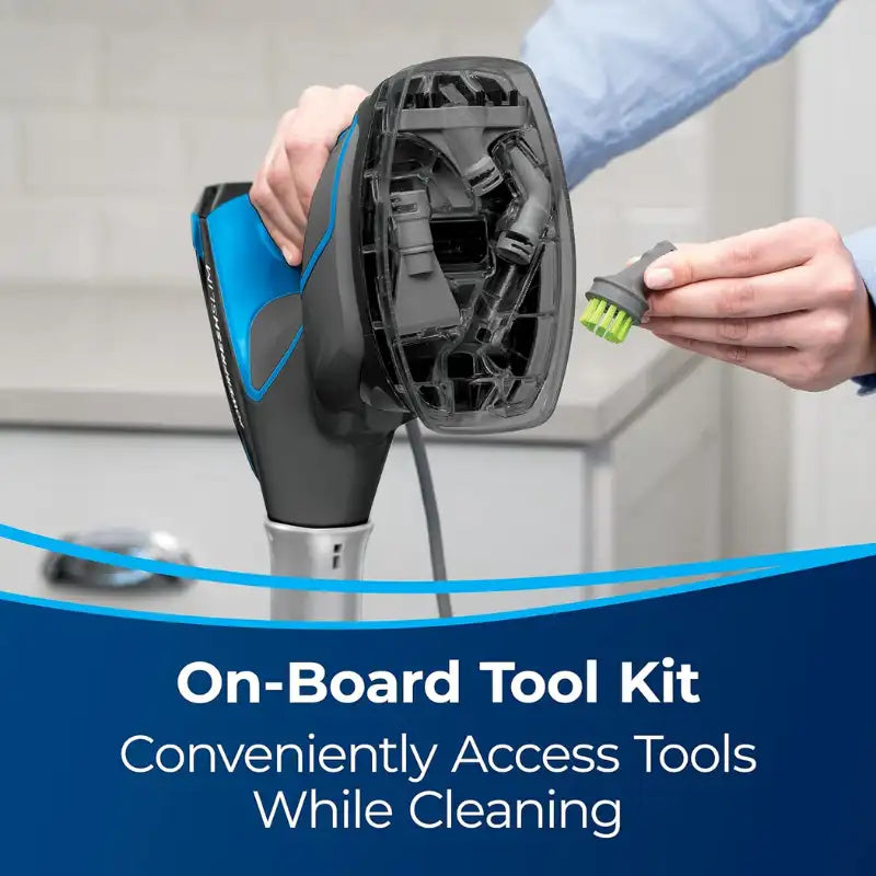 A person's hands demonstrate how to access on-board cleaning tools on a handheld steam cleaner, with a blue and black steam cleaner and a small green-bristled tool shown. A blue banner at the bottom reads 'On-Board Tool Kit Conveniently Access Tools While Cleaning'.
